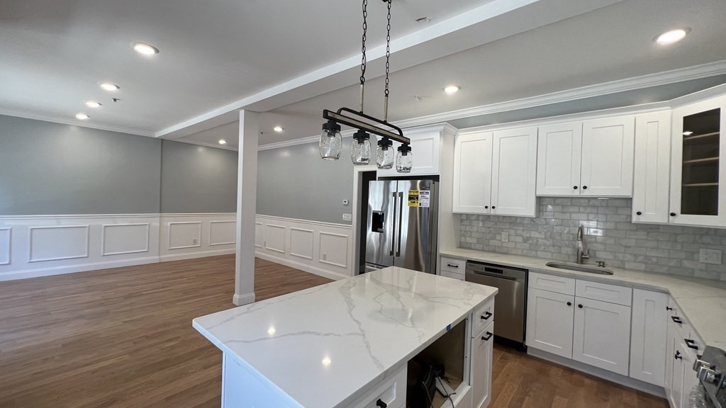 a kitchen with kitchen island a counter top space a sink stainless steel appliances and cabinets