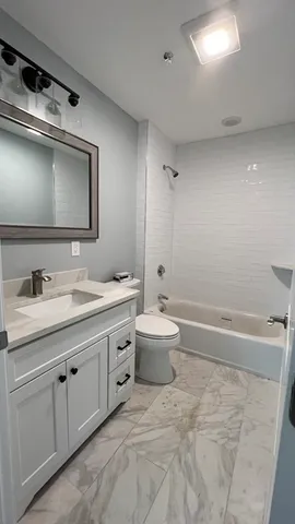 a bathroom with a double vanity sink and mirror with toilet