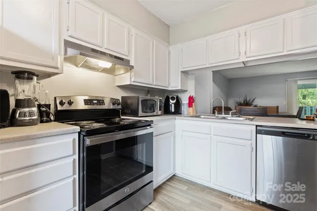 a kitchen with stainless steel appliances granite countertop a stove and white cabinets