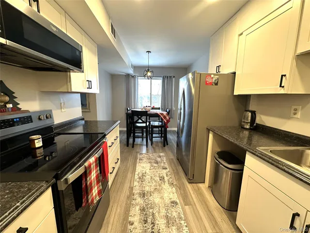 a kitchen with granite countertop a sink a counter space and stainless steel appliances