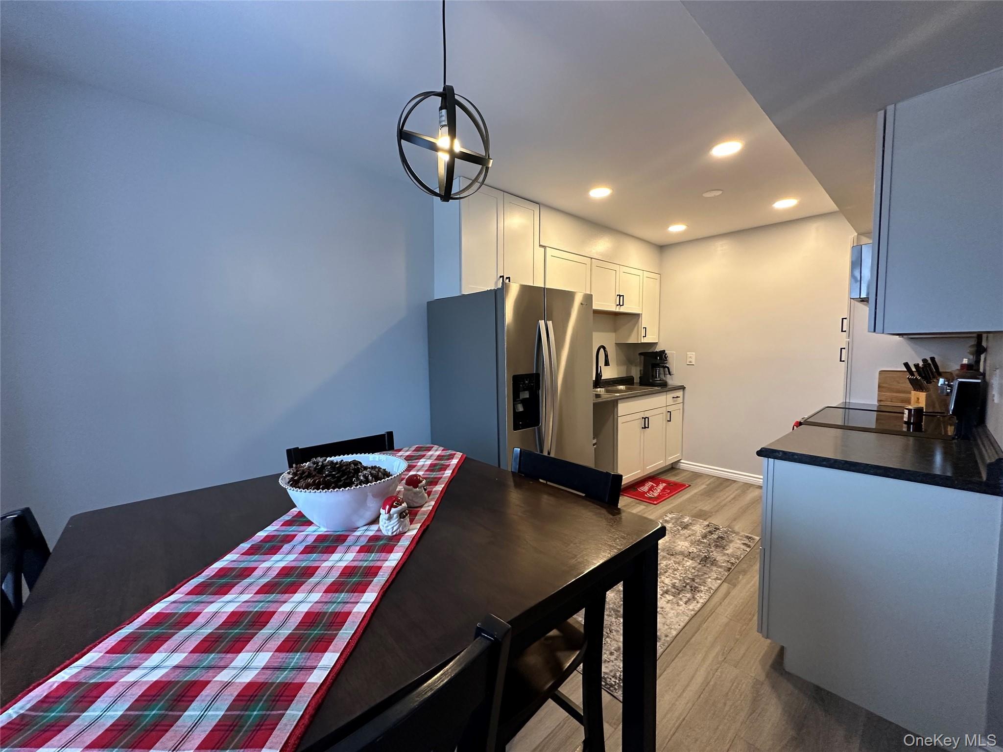 26 Cooper, Unit 510 Poughkeepsie, NY 12603 - Photo 4 of 28 Kitchen featuring dark countertops, stainless steel fridge, light wood-style flooring, white cabinetry, and recessed lighting