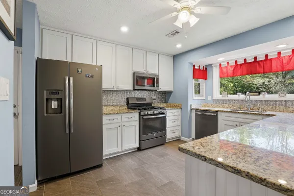 a kitchen with granite countertop a stove top oven and refrigerator