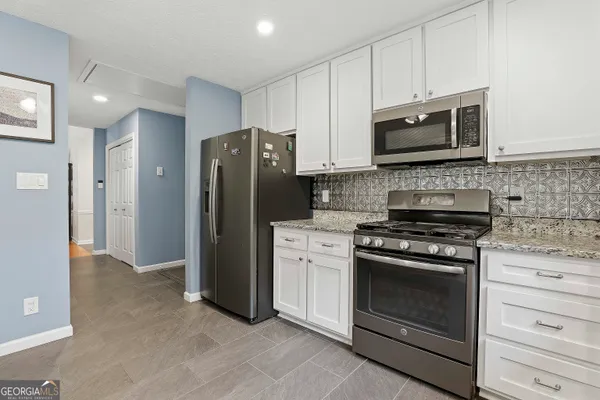 a kitchen with stainless steel appliances white cabinets a stove a microwave and a refrigerator