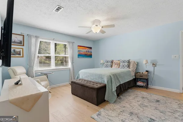 a spacious bedroom with a bed and wooden floor