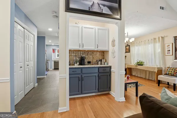 a room with stainless steel appliances kitchen island granite countertop a refrigerator a stove a microwave oven with white cabinets and wooden floor