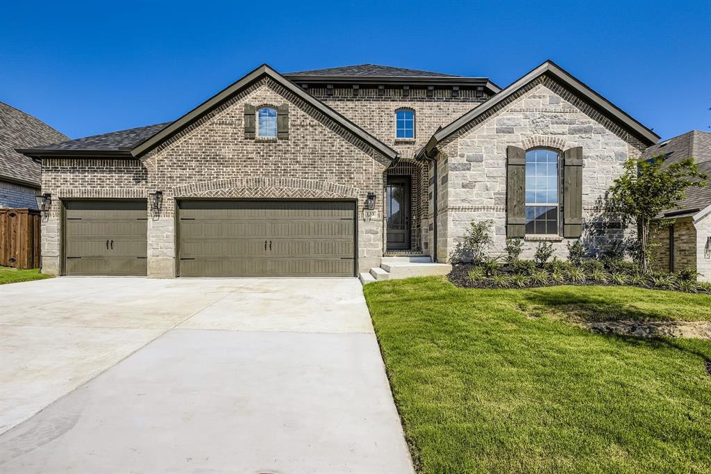 French country style house featuring brick siding, driveway, and a front yard