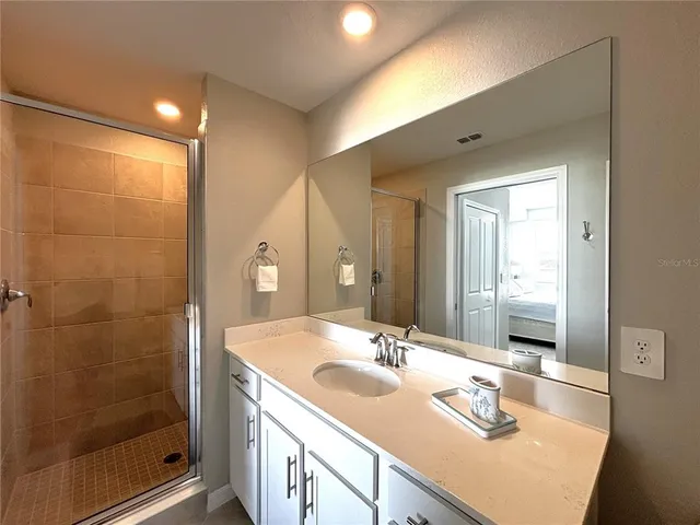 a bathroom with a sink vanity granite shower and a mirror
