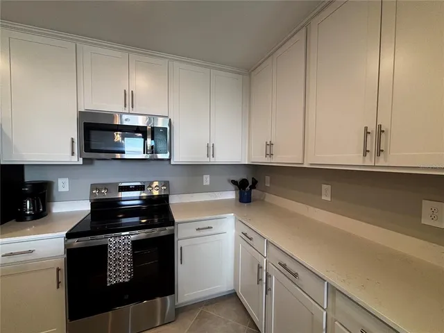 a kitchen with granite countertop white cabinets and black appliances