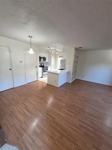 a view of a kitchen with kitchen island a sink wooden floor and living room view