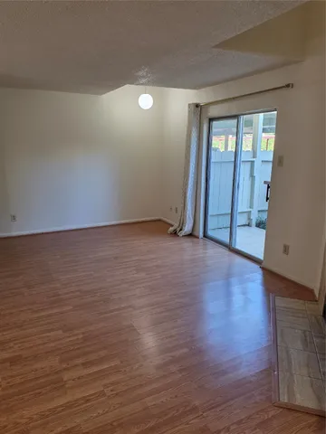 a view of an empty room with window and wooden floor