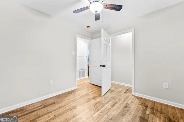 an empty room with wooden floor and ceiling fan