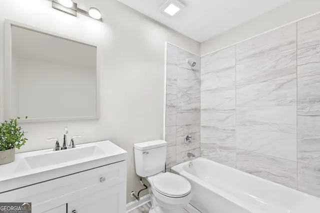 a bathroom with a bathtub shower sink mirror vanity and toilet