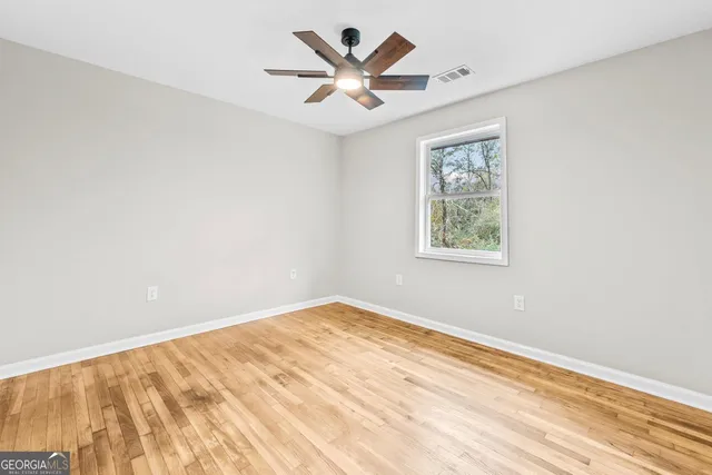 an empty room with wooden floor and ceiling fan