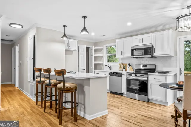 a kitchen with stainless steel appliances granite countertop a stove top oven a sink dishwasher a dining table and chairs with wooden floor