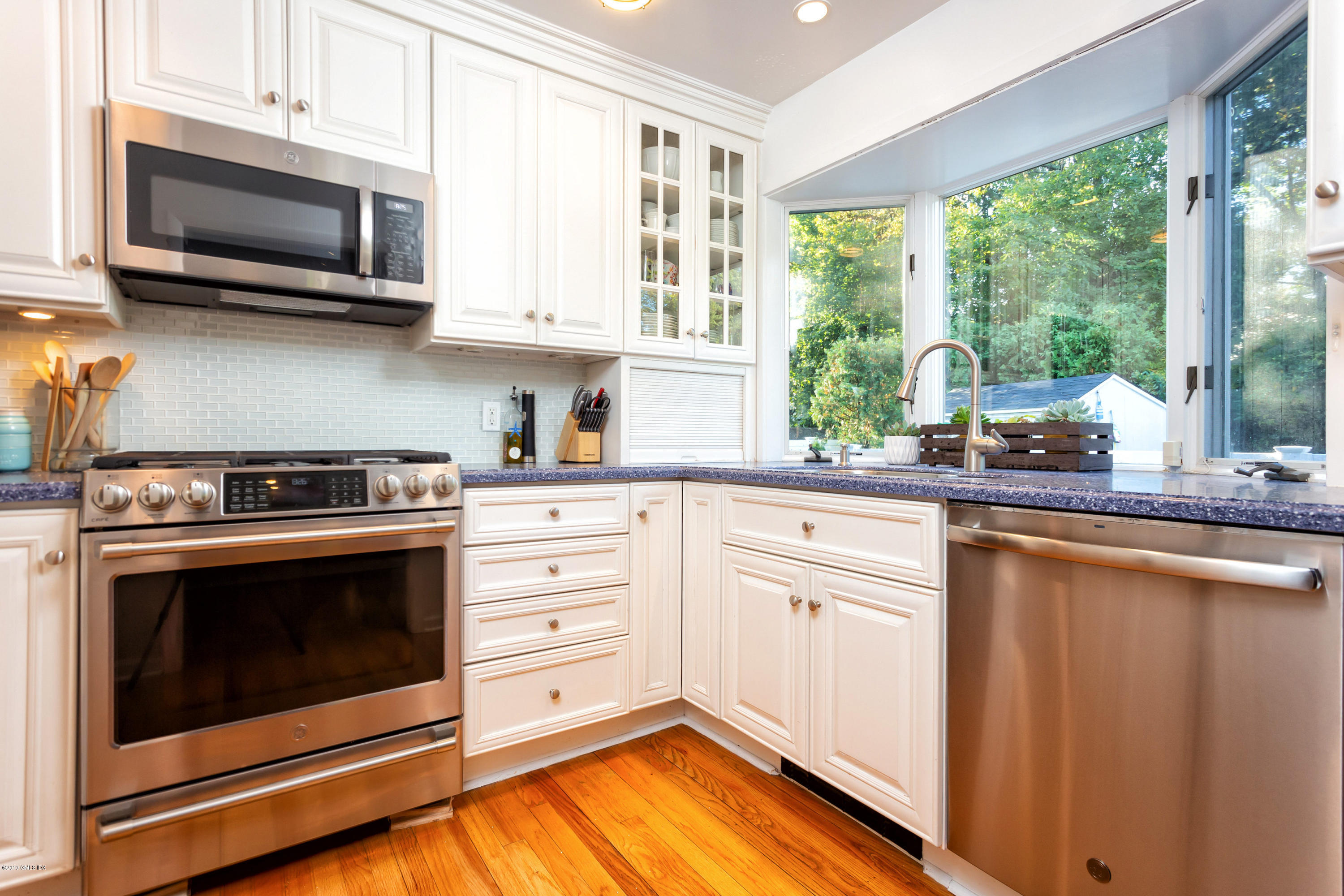 12 Mary Lane Riverside, CT 06878 - Photo 11 of 25 a kitchen with stainless steel appliances white cabinets a stove a microwave and a window