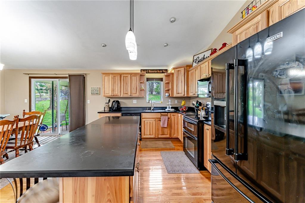 321 Eighmy Road Pittsburgh, PA 15239 - Photo 5 of 24 a kitchen with stainless steel appliances granite countertop a stove top oven a sink a dining table and chairs with wooden floor