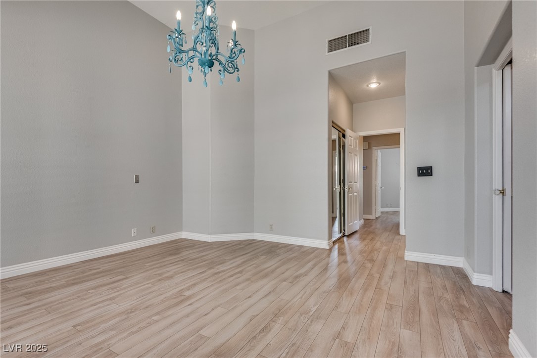 8541 Heather Downs Drive Las Vegas, NV 89113 - Photo 16 of 39 Empty room with a chandelier, light wood-type floo