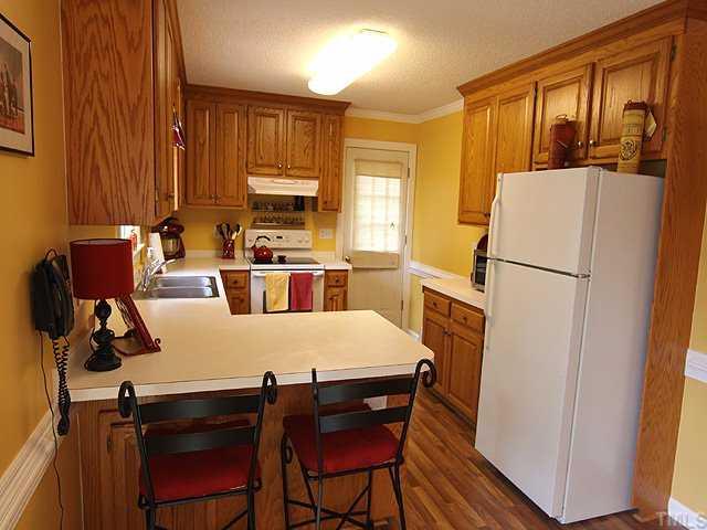 1109 Riderwood Court Willow Spring, NC 27592 - Photo 3 of 11 Terrific kitchen with lots of oak cabinets and counter space including a large breakfast bar! New laminated flooring and side entry door, smooth top range and more moulding complete this wonderful kitchen!