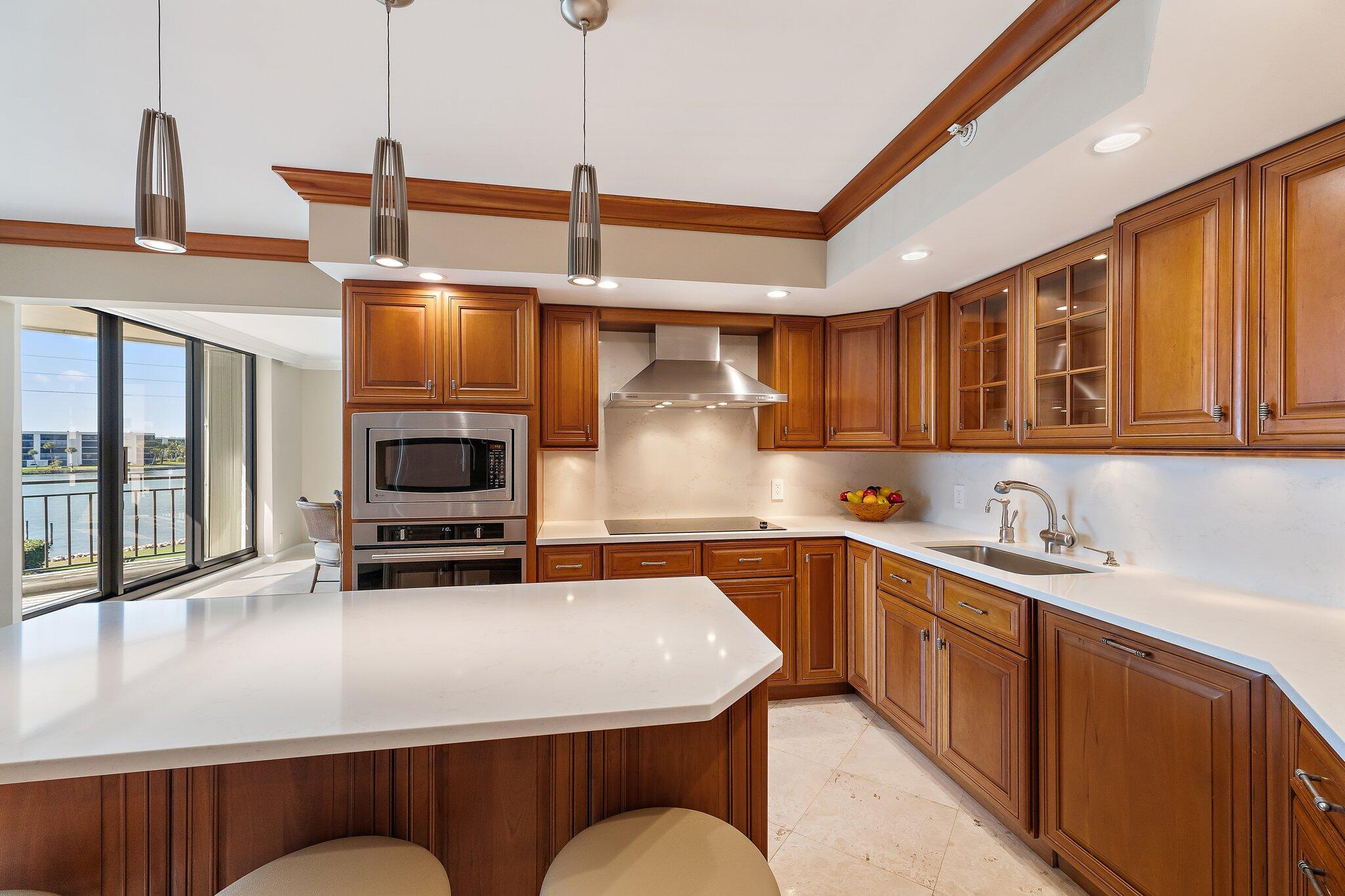 19850 South Beach Road, Unit 3D Jupiter, FL 33469 - Photo 25 of 54 a kitchen with stainless steel appliances granite countertop a sink a stove and a wooden cabinets