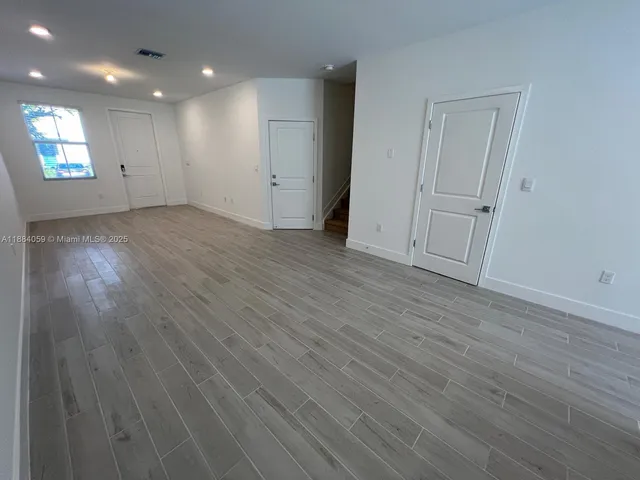an empty room with wooden floor and entrance