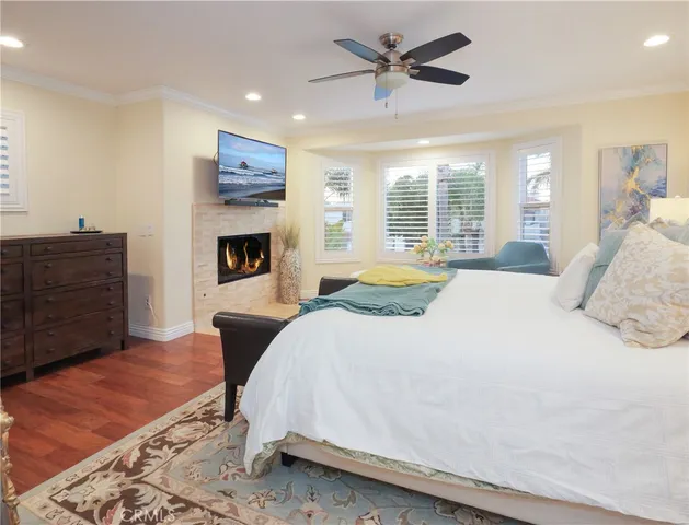 a spacious bedroom with a bed a dresser and wooden floor