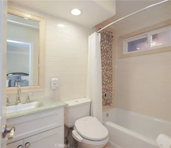 a bathroom with a bathtub shower sink vanity mirror and toilet