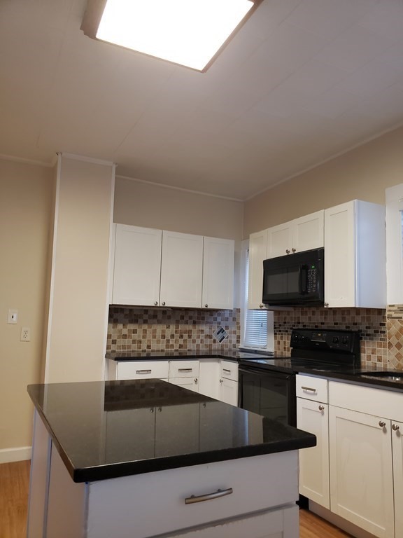 55 Tyler Street Springfield, MA 01109 - Photo 16 of 32 a kitchen with granite countertop white cabinets and black appliances