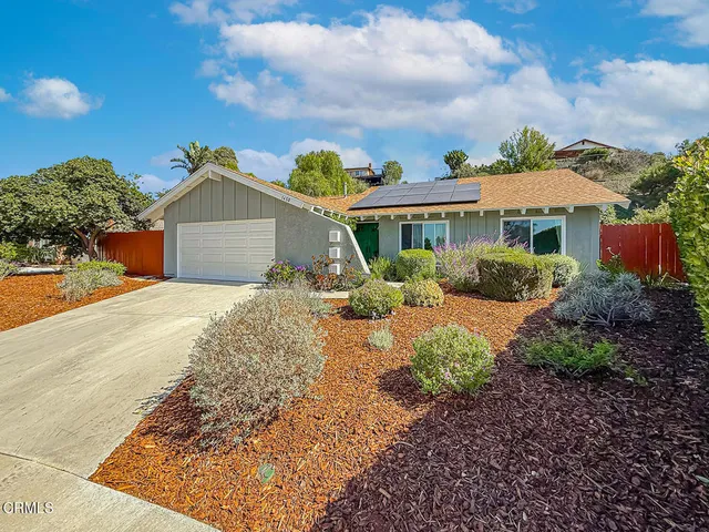 a front view of a house with a yard and potted plants
