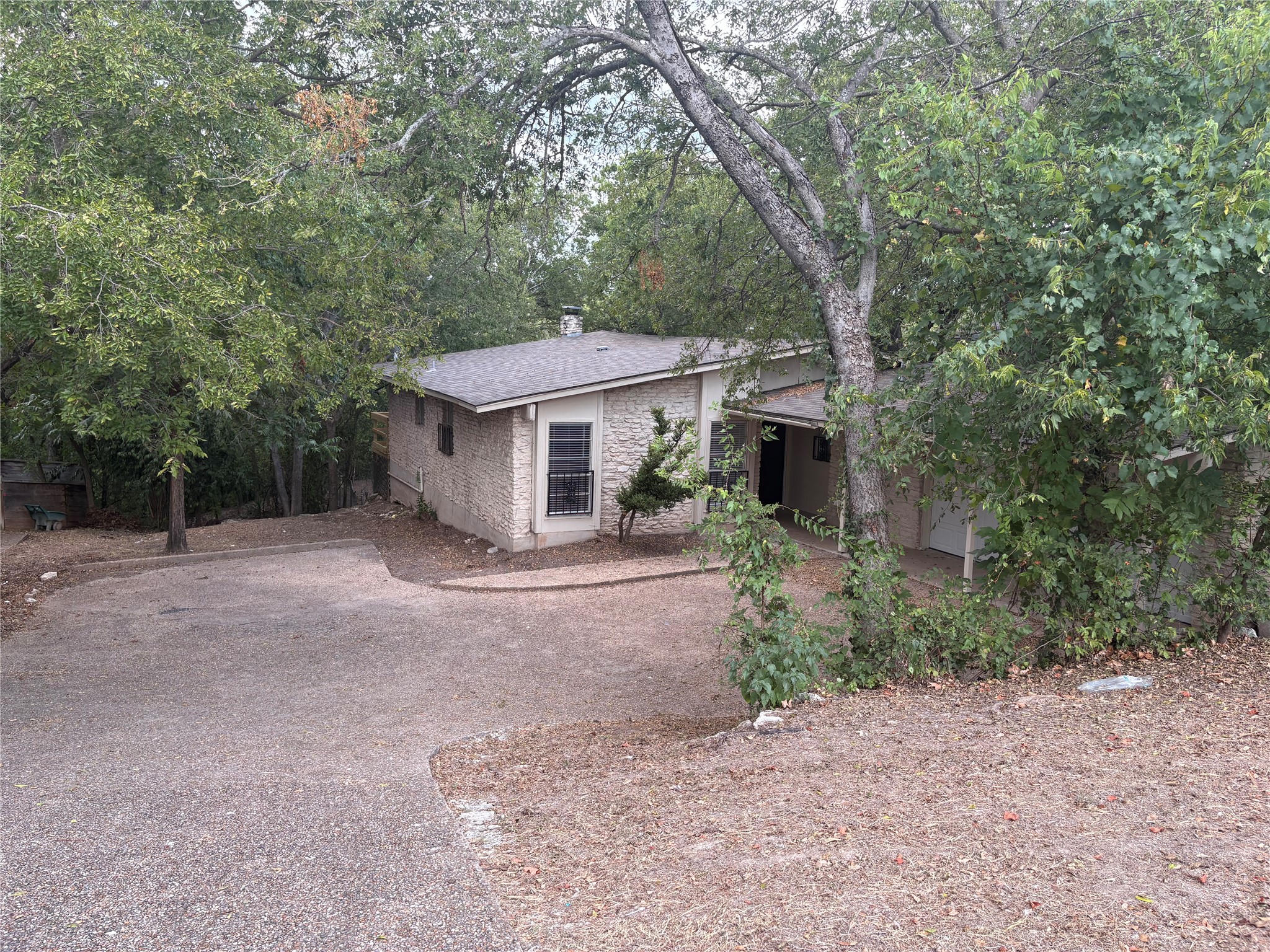 11913 Rennalee Loop Austin, TX 78753 - Photo 40 of 40 A secluded dwelling with stone siding and a winding driveway, nestled among mature trees.