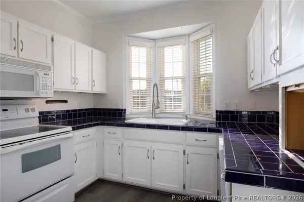 a kitchen with granite countertop white cabinets and white appliances
