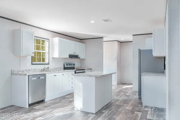 a kitchen with stainless steel appliances a sink a stove a refrigerator cabinets and a window