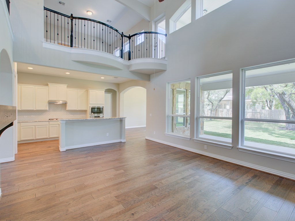 4303 Logan Ridge Drive Cedar Park, TX 78613 - Photo 5 of 24 Spacious open-concept interior featuring wood-finish flooring, soaring ceilings, and a second-story balcony with wrought iron railing