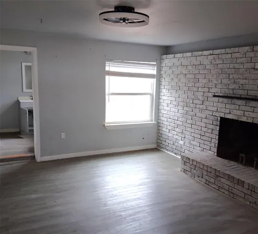 a view of empty room with wooden floor and fireplace