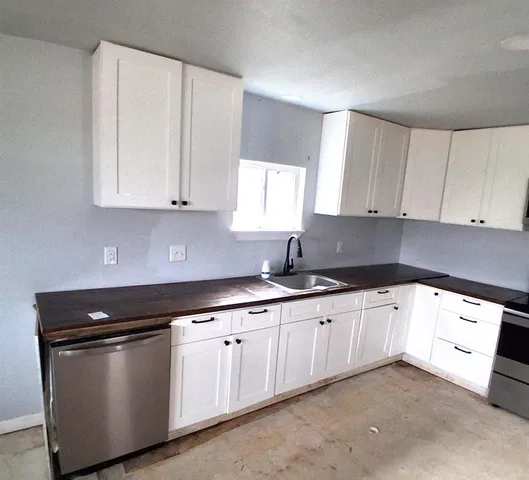 a kitchen with granite countertop white cabinets and sink