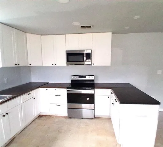 a kitchen with granite countertop white cabinets and black appliances