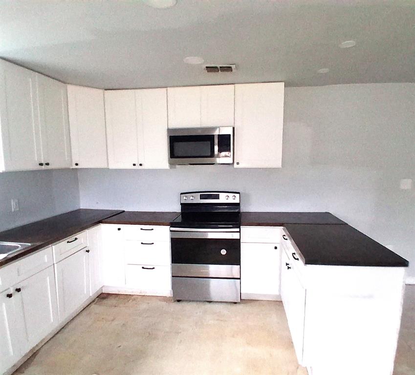 7019 Darling Street Azle, TX 76020 - Photo 8 of 19 a kitchen with granite countertop white cabinets and black appliances