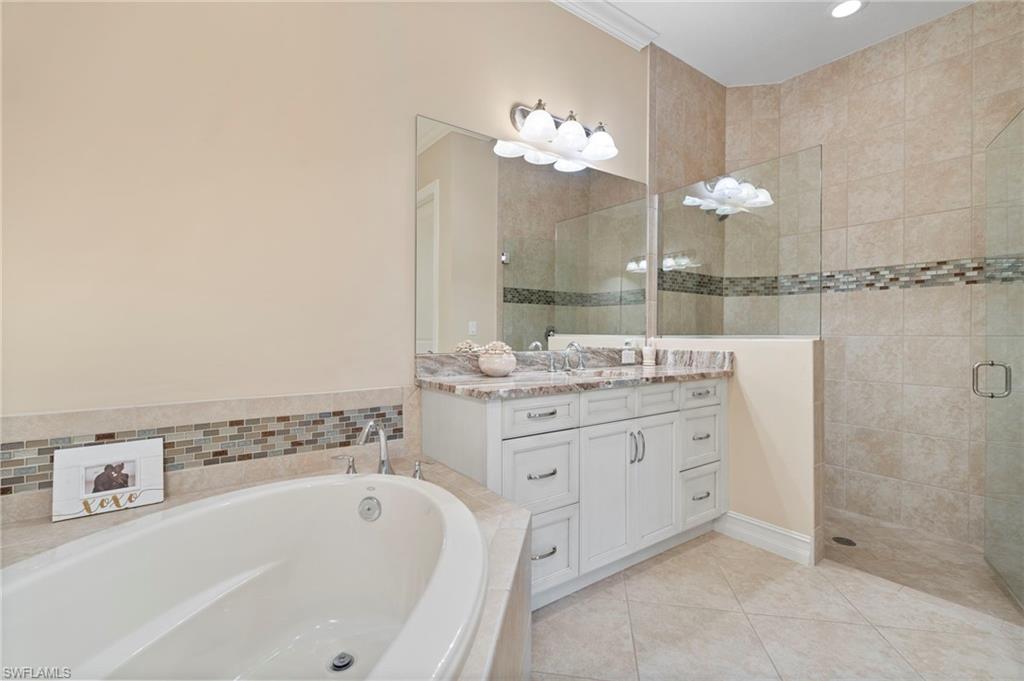 6564 Roma Way Naples, FL 34113 - Photo 14 of 18 a bathroom with a bathtub sink and mirror