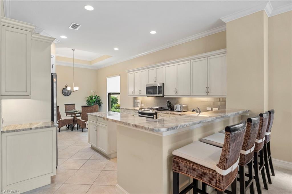 6564 Roma Way Naples, FL 34113 - Photo 6 of 18 a kitchen with a dining table chairs and refrigerator