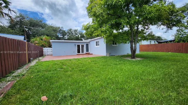 a view of a house with backyard and a tree