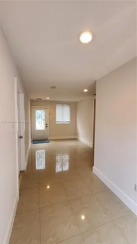 a view of a hallway with wooden floor and a living room