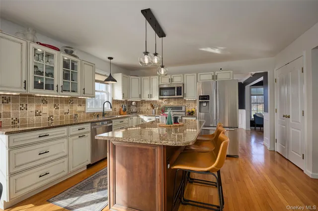 a large kitchen with kitchen island a dining table chairs wooden cabinets and stainless steel appliances