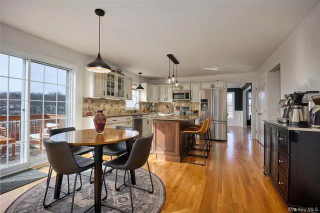 a view of a dining room and livingroom with furniture wooden floor a rug a flat screen tv a painting and a chandelier