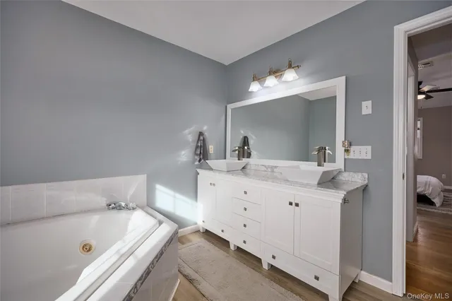 a bathroom with a tub a double vanity sink and a mirror