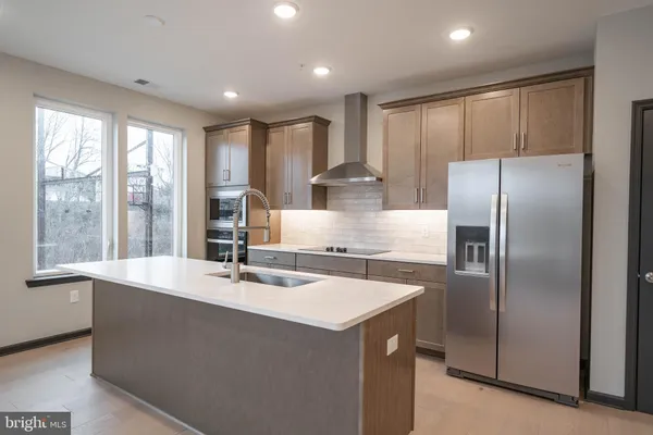 a kitchen with kitchen island a large counter top space appliances and a large window