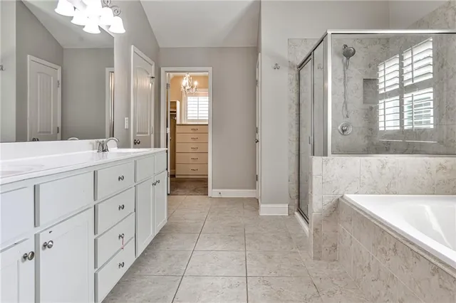 a spacious bathroom with a double vanity sink a mirror a bathtub and next to a window