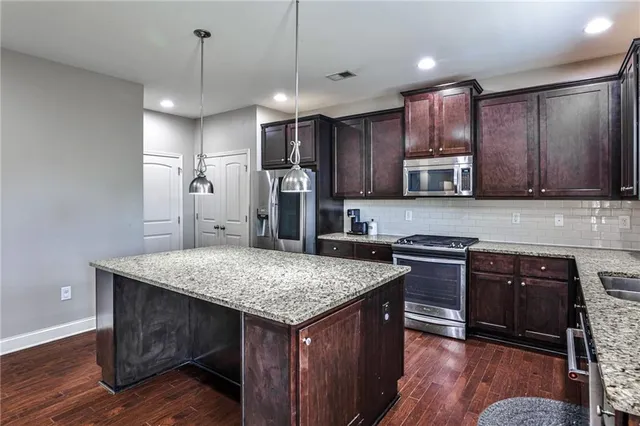 a kitchen with stainless steel appliances granite countertop a kitchen island hardwood floor sink stove and refrigerator