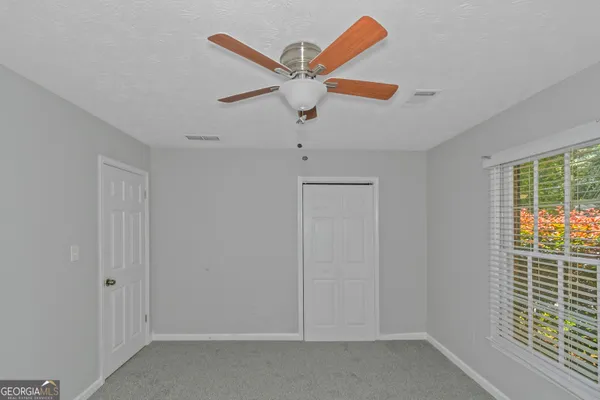 an empty room with a window and a fan