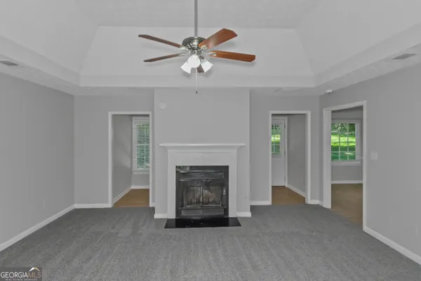 a view of an empty room with chandelier fan and fire place