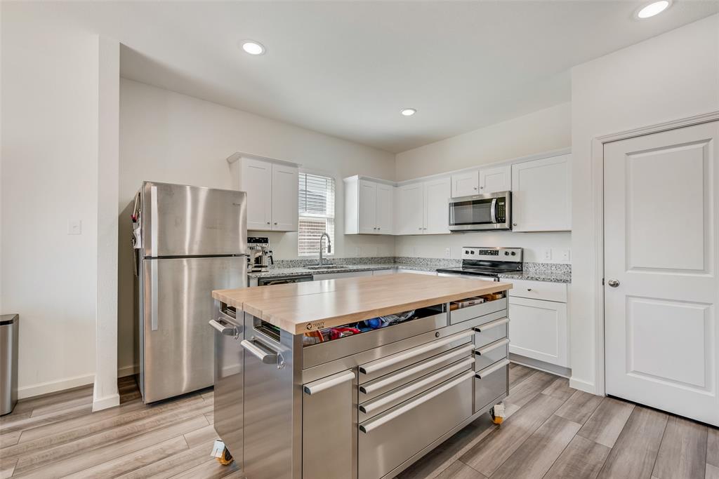 2544 Sanders Crk Road Glenn Heights, TX 75154 - Photo 7 of 20 a kitchen with stainless steel appliances granite countertop a refrigerator a stove a sink and white cabinets with wooden floor