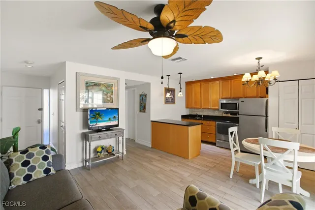 a kitchen with stainless steel appliances kitchen island granite countertop a refrigerator a stove a microwave oven a dining table and chairs with wooden floor